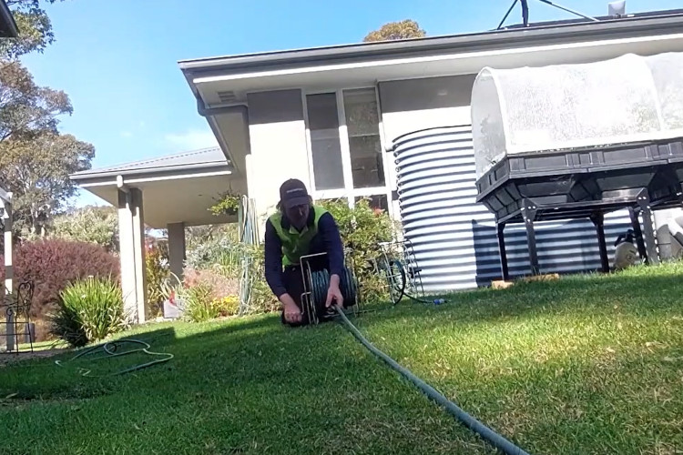 
The portstephens downpipe cleaner is putting his hose away, marking the end of the day`s tasks.